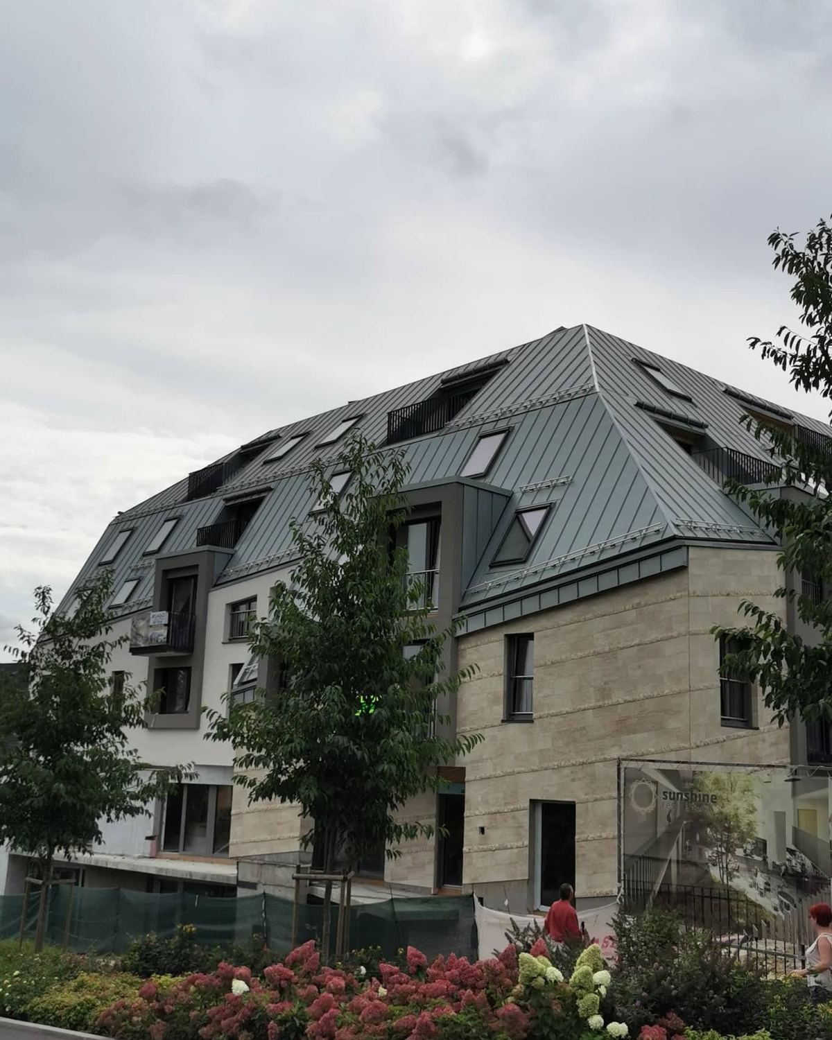 Fémlemezzel fedett, tetőablakos többszintes lakóépület, a Constructor Hungária Kft. munkája